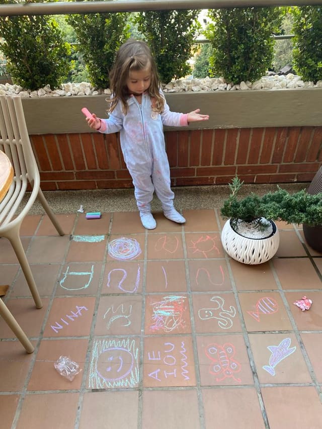 A child drawing on a patio with chalk, lost in independent play
